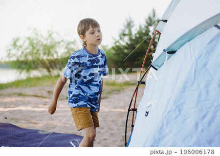 cute little caucasian boy helping to put up a tent. Family camping concept 106006178