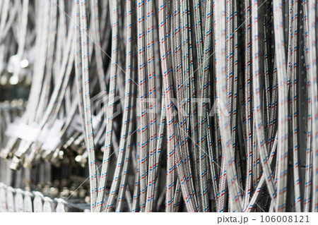 Closed up braided stainless steel texture of flexible hose arranged in a row against white wall. 106008121