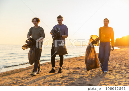 Earth day. Volunteers activists collects garbage cleaning of beach coastal zone. Woman mans with trash in garbage bag on ocean shore. Environmental conservation coastal zone cleaning. Blurred video 106012841