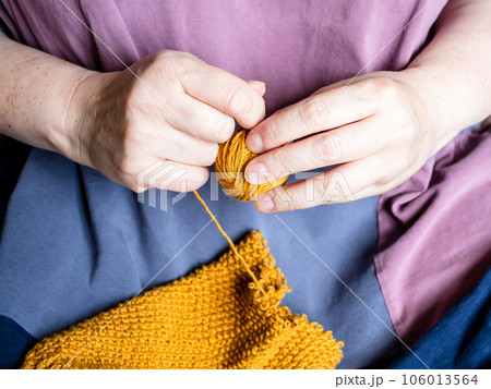 hands winding ball of yarn from knitted sweater 106013564