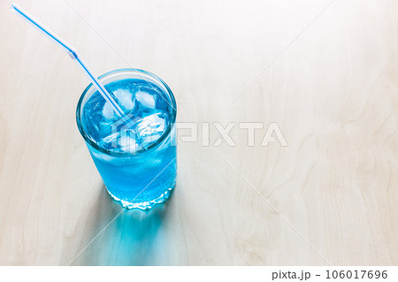 blue cocktail in glass with drinking straw 106017696
