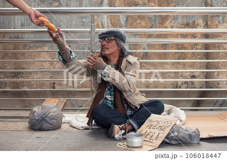 Aged homeless beggar reach out to get bread on donor hand at the bridge 106018447