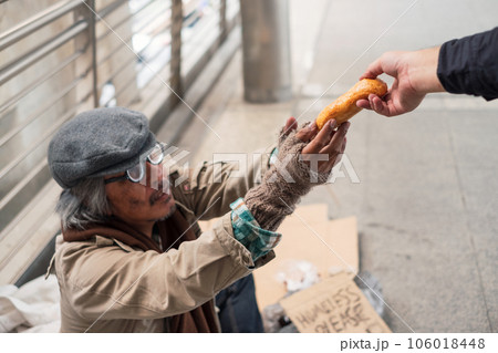 Aged homeless beggar reach out to get bread on donor hand at the bridge 106018448