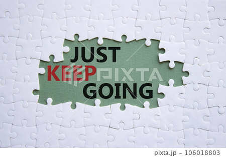Just keep going symbol. White puzzle with words Just keep going. Beautiful grey green background. Business and Just keep going concept. Copy space. 106018803