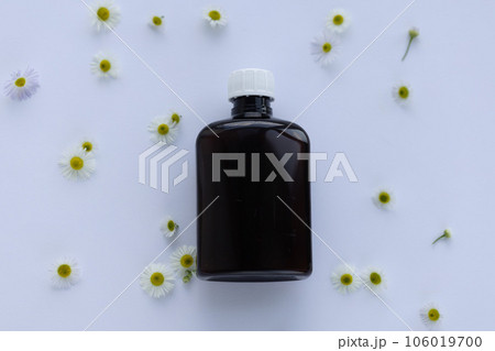 Bottle container with camomile flowers around it. Natural organic beauty product concept. 106019700