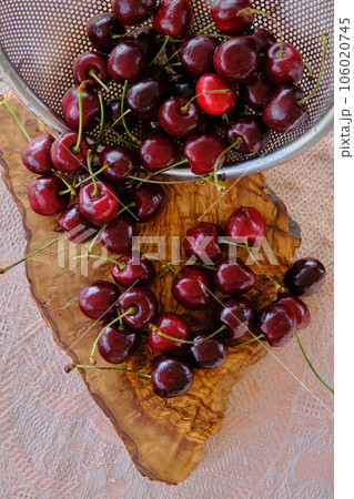 ripe cherries scattered on a wooden board 106020745