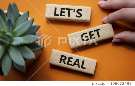 Lets get real symbol. Concept words Lets get real on wooden blocks. Beautiful orange background. Businessman hand. Business and Lets get real concept. Copy space. 106022498