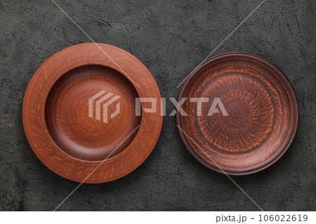Two Rustic Plates on gray background. Empty brown clay plate on black stone table. Top view with copy space. Rustic dishes Two Rustic Plates on gray background. Empty brown clay plate on black stone table. Top view with copy space. Rustic dishes 106022619