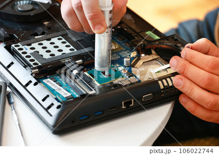 Hand a repairman uses thermal paste syringe apply thermal compound to a CPU. Master replaces thermal grease. Professional service and repair tech and electronics devices, laptops and PC 106022744