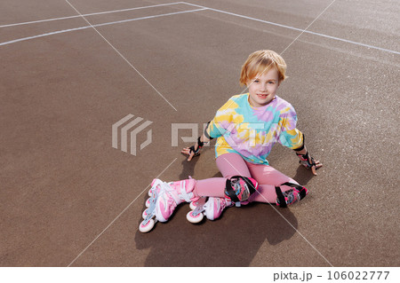 A beautiful little girl learns to roller skate  106022777