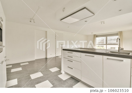 an empty kitchen with white cabinets and black counter tops on the floor in front of the door is a window 106023510