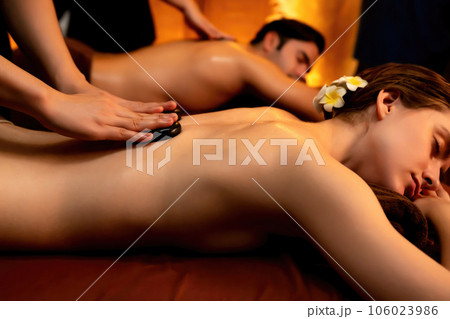 Hot stone massage at spa salon in luxury resort with warm candle light.Quiescent Hot stone massage at spa salon in luxury resort with warm candle light.Quiescent 106023986