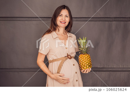 A pregnant woman's belly, beautifully showcasing the size of her baby, likened to a pineapple. Explore the potential benefits and harms of pineapple during pregnancy and childbirth 106025624