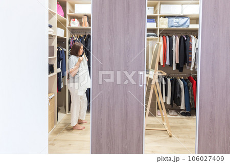 Woman in big walkin closet choosing clothes. modern wardrobe and dressing room with copy space 106027409