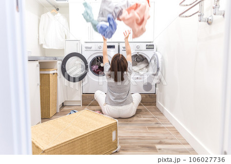 Happy family mother housewife in laundry room with washing machine throwing clothes up 106027736