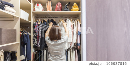 Woman in big walkin closet choosing clothes. modern wardrobe and dressing room with copy space Woman in big walkin closet choosing clothes. modern wardrobe and dressing room with copy space 106027816