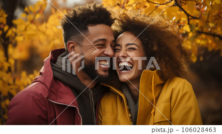 Happy warmly dressed young loving multi-ethnic couple laughing as they enjoy the beautiful fall leaves in the park - Generative AI. Happy warmly dressed young loving multi-ethnic couple laughing as they enjoy the beautiful fall leaves in the park - Generative AI. 106028463