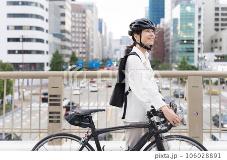 ロードバイクを引いて歩くアラフィフのビジネスウーマン ロードバイクを引いて歩くアラフィフのビジネスウーマン 106028891