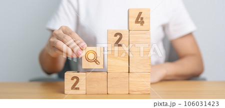hand holding 2024 block with magnifying glass icon. SEO, Search Engine Optimization, hiring , Advertising, Idea, Strategy, marketing, Keyword, Content and New Year start concepts 106031423