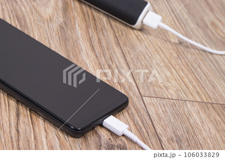 External powerbank using to charge empty battery of black smartphone 106033829