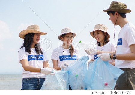 Group of Asian young people volunteer helping to collecting or picking up a plastic bottle garbage on the ground in park. Sustainability and environment conservation concept. 106036270