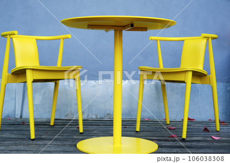 Yellow chairs and a table stand on the summer terrace of a city cafe 106038308