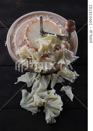 Slice the tete des Moines cheese with a girolle knife. A kind of Swiss semi-hard cheese. A special cheese knife.Vertical photo. Slice the tete des Moines cheese with a girolle knife. A kind of Swiss semi-hard cheese. A special cheese knife.Vertical photo. 106038782