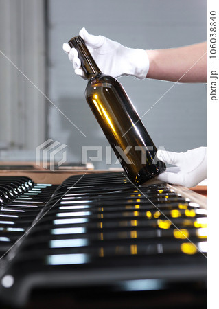 Wine storage.New wine is bottled and stacked.Bottled wine at winery.Hands in white gloves. Wine storage.New wine is bottled and stacked.Bottled wine at winery.Hands in white gloves. 106038840