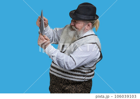 Portrait of excited senior man playing video game on tablet pc. Isolated on blue. 106039103