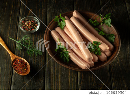 Raw pork sausages on a vintage plate with parsley and spices. Fast food or street food concept 106039504
