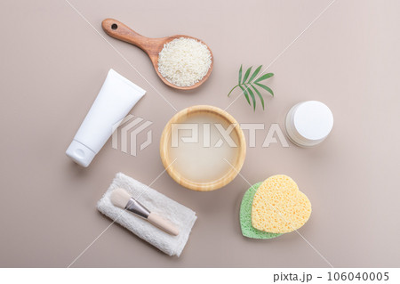 Homemade cosmetic rice water with beauty kit on beige background, top view copy space, home spa flat lay 106040005