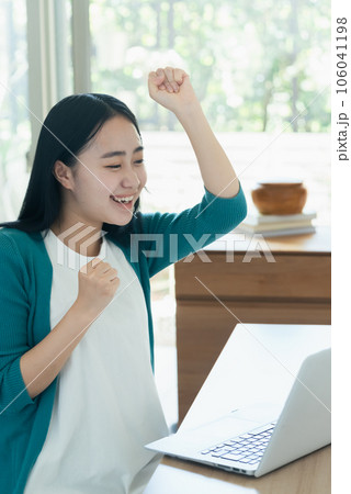パソコンの前で喜ぶ若い女性 106041198