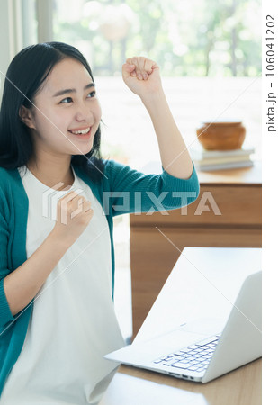 パソコンの前で喜ぶ若い女性 106041202