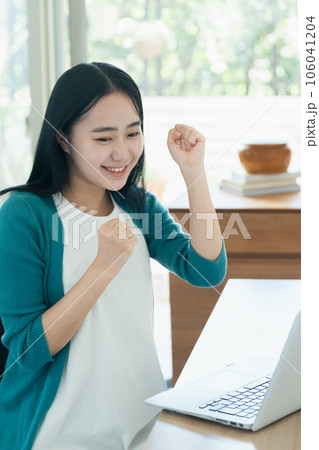 パソコンの前で喜ぶ若い女性 106041204