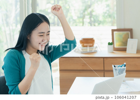 パソコンの前で喜ぶ若い女性 106041207