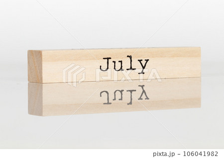 wooden cube with the inscription July on a white background 106041982