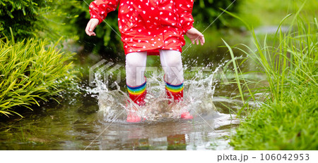Kids in puddle in autumn rain. Waterproof wear Kids in puddle in autumn rain. Waterproof wear 106042953