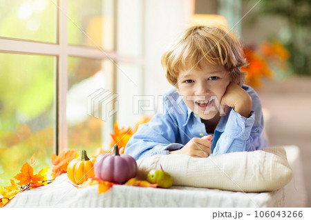 Child at window in autumn. Kids at home in fall. Child at window in autumn. Kids at home in fall. 106043266