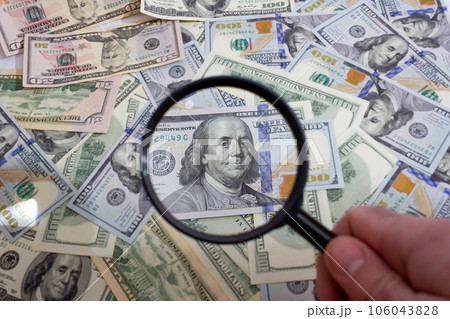 Magnifying glass on the background of bundle dollars - texture, background 106043828