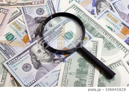 Magnifying glass on the background of bundle dollars - texture, background 106043829