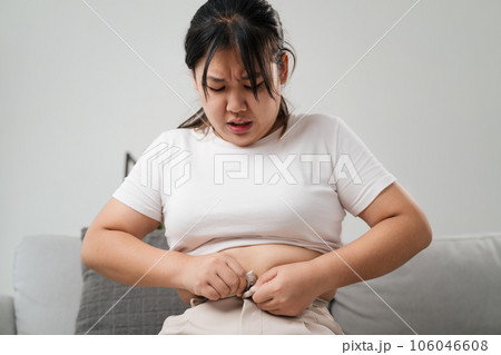 Fat chubby woman trying to wear tight pants, overweight, weight gain, Healthy and medical concept. Fat chubby woman trying to wear tight pants, overweight, weight gain, Healthy and medical concept. 106046608