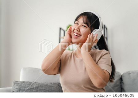 Young woman listening to music with headphone and relaxing while sitting on the sofa at home. 106046609