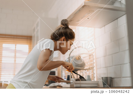 Woman in white t-shirt cooking in the kitchen making lunch. Woman in white t-shirt cooking in the kitchen making lunch. 106048242