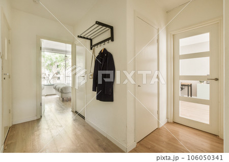 the inside of a house with wood floors and white walls, there is a coat rack hanging on the wall 106050341