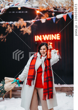 an attractive brunette woman with champagne and a bouquet of spruce branches. 106050873