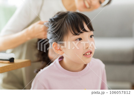 母親に髪をブラッシングしてもらう女の子 106057812