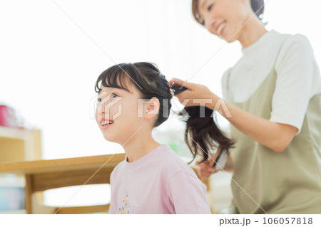 母親に髪をブラッシングしてもらう女の子 106057818