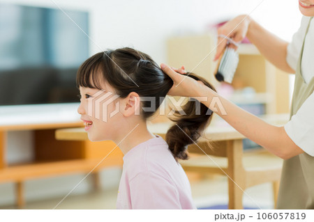母親に髪をブラッシングしてもらう女の子 106057819