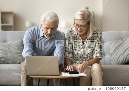 Focused couple of senior homeowners doing domestic accounting work together Focused couple of senior homeowners doing domestic accounting work together 106060127