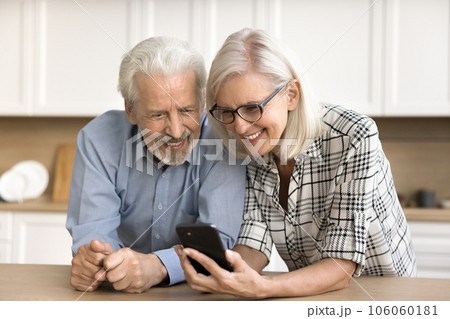 Positive mature retired husband and wife using mobile phone together 106060181